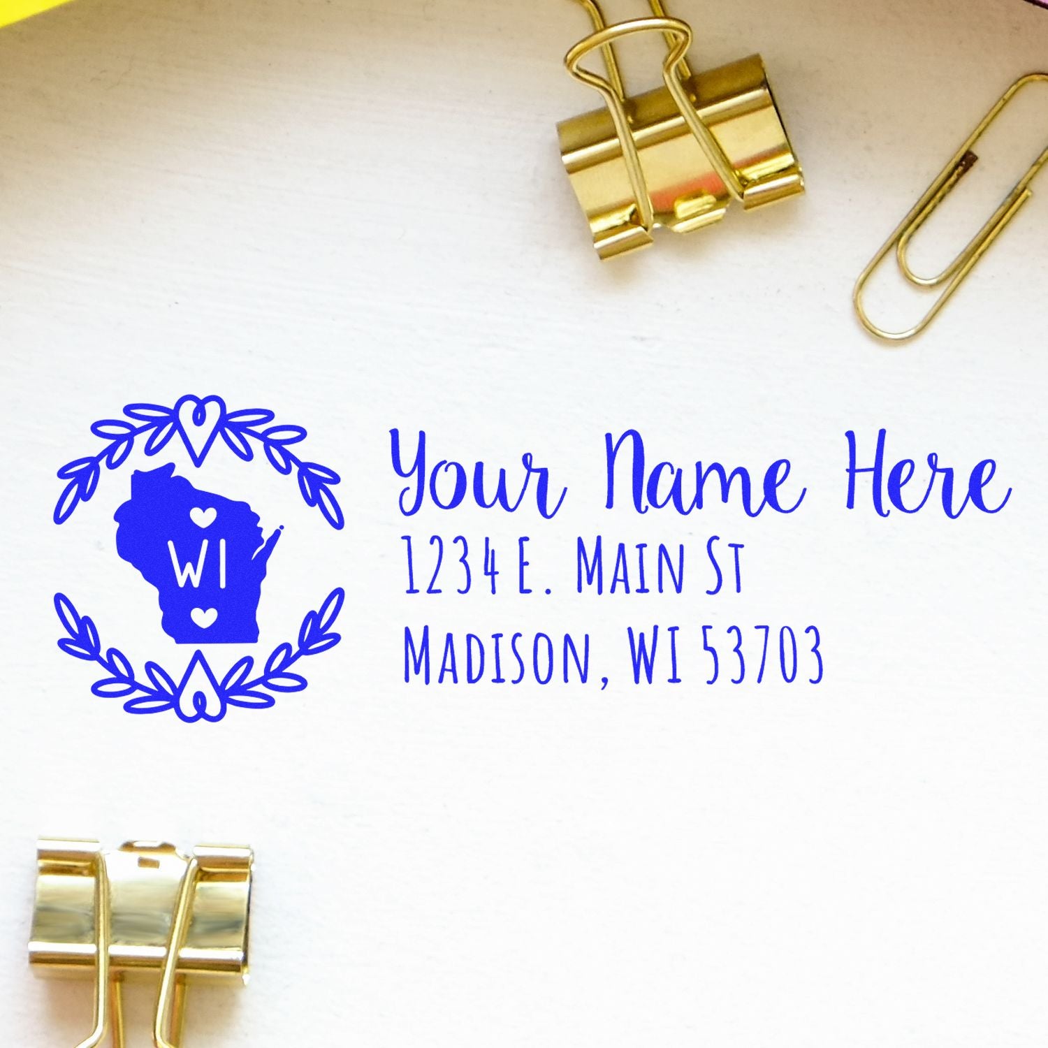 Wisconsin State Custom Return Address Stamp on white paper with gold binder clips. Features a blue outline of Wisconsin with WI inside, surrounded by a heart wreath, and sample address text.