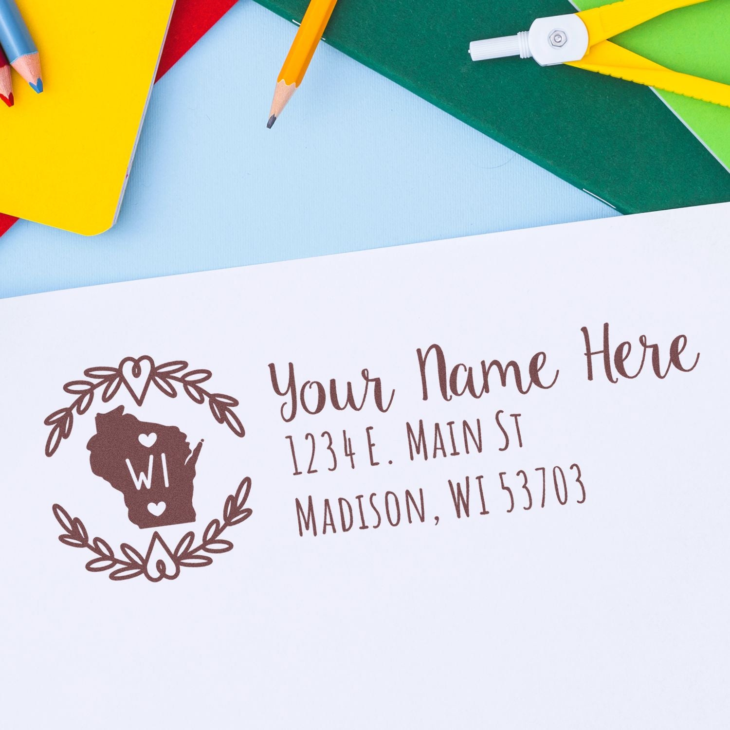 PSI Pre-Inked Wisconsin State Customized Address Stamp on white paper with colorful stationery. Features a Wisconsin outline with hearts and floral design, showcasing a sample address in elegant font.