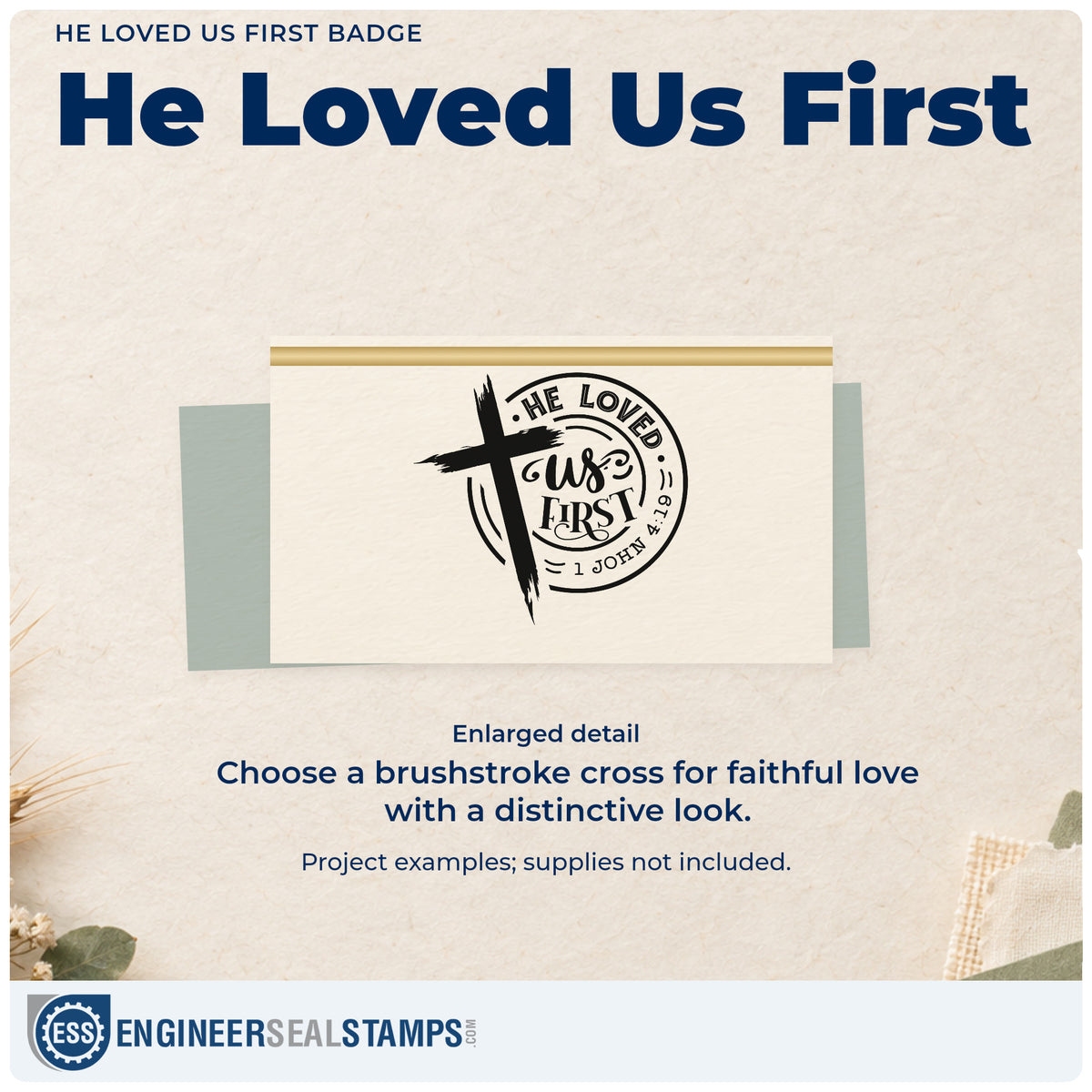 Enlarged detail of the He Loved Us First Emblem Stamp – Wood Handle imprint. A brushstroke cross overlaps a circular "He loved us first" design with 1 John 4:19.