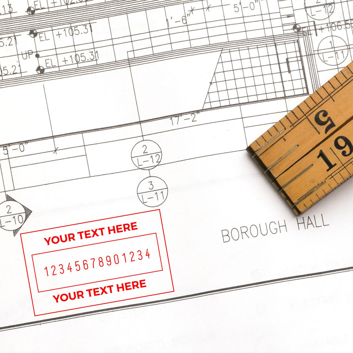 Red custom rubber stamp design on an architectural blueprint, with a wooden seal/ruler and black plan lines.