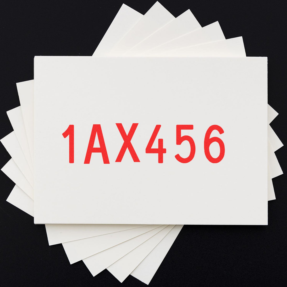 White stamp and seal sample cards fanned on black background, with bold red 1AX456 code on front card.