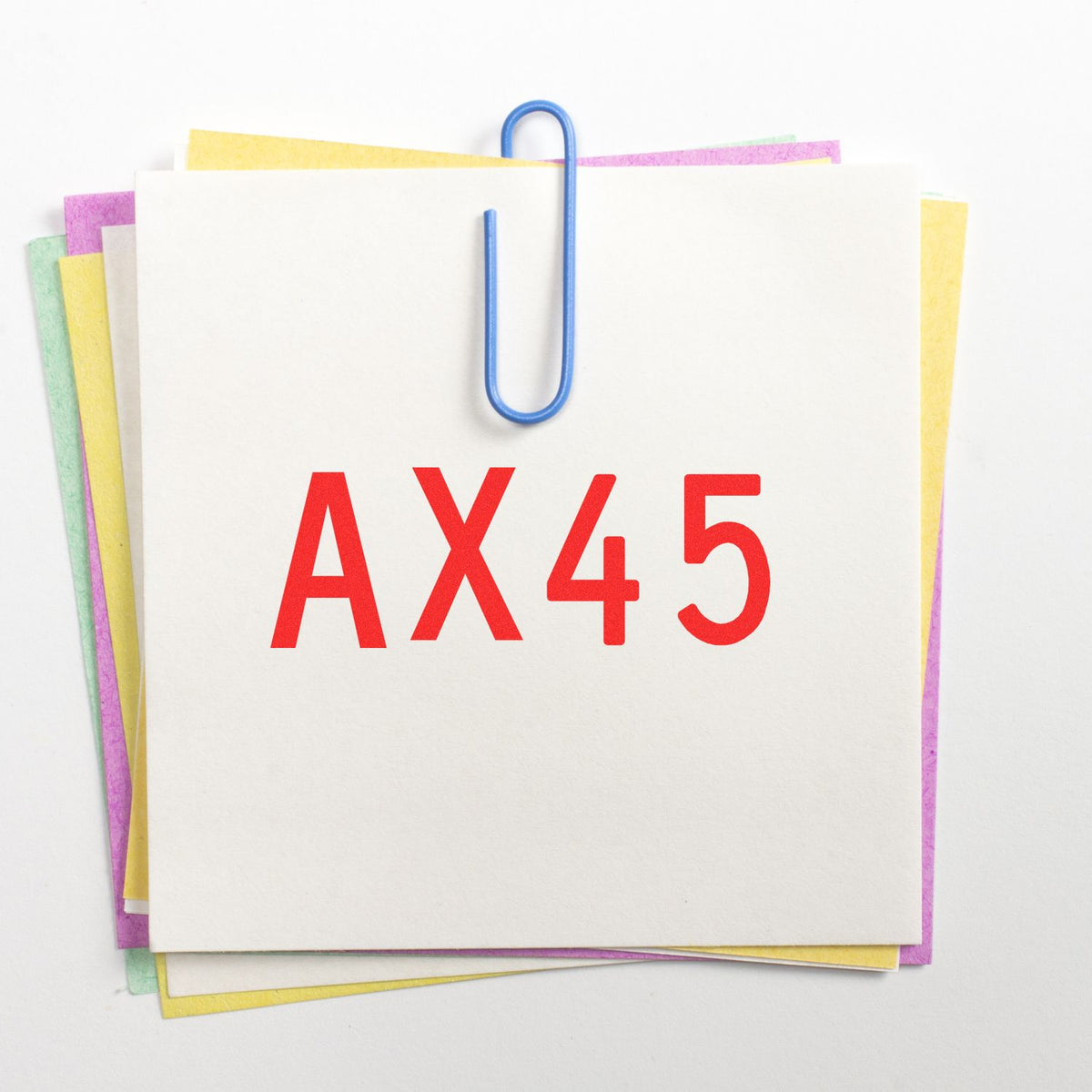 AX45 red stamp on stacked white sheets clipped with a blue paperclip, backed by pastel pink, yellow, green, and purple seals