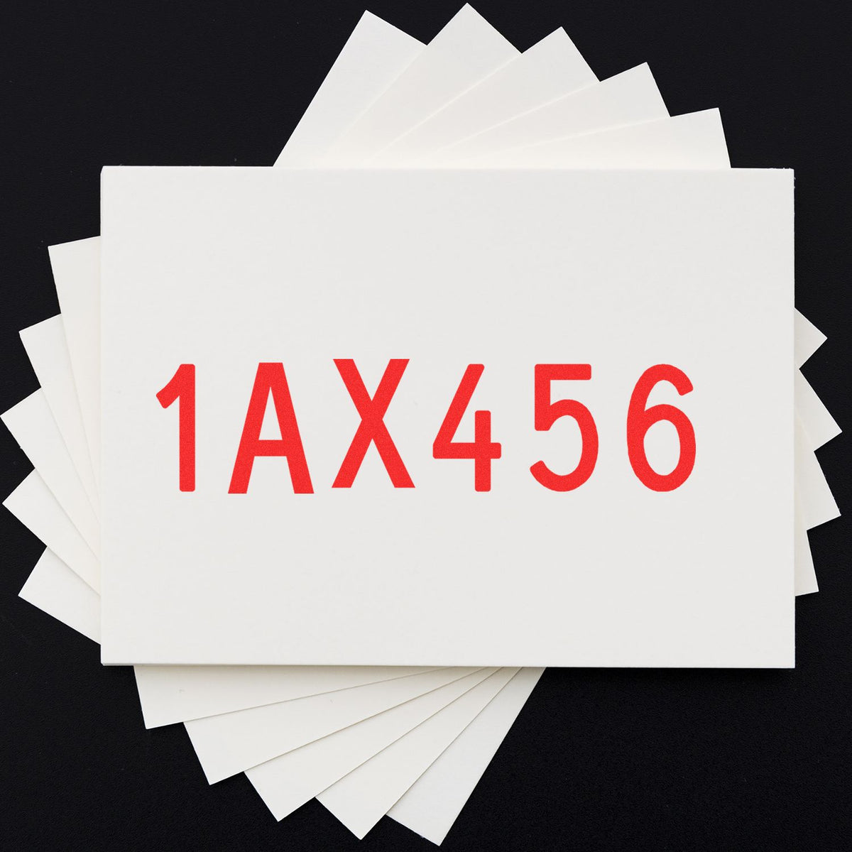 White stamp and seal sample cards fanned on black background with bold red 1AX456 code