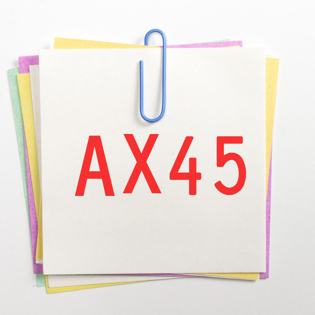 AX45 stamp and seal products on stacked pastel papers, clipped with a blue paperclip