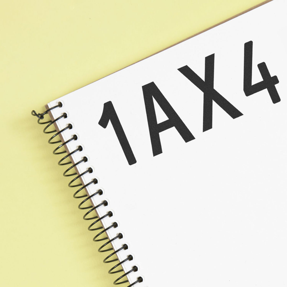 White spiral-bound stamp and seal product notebook with bold black 1AX4 text on a pale yellow background.