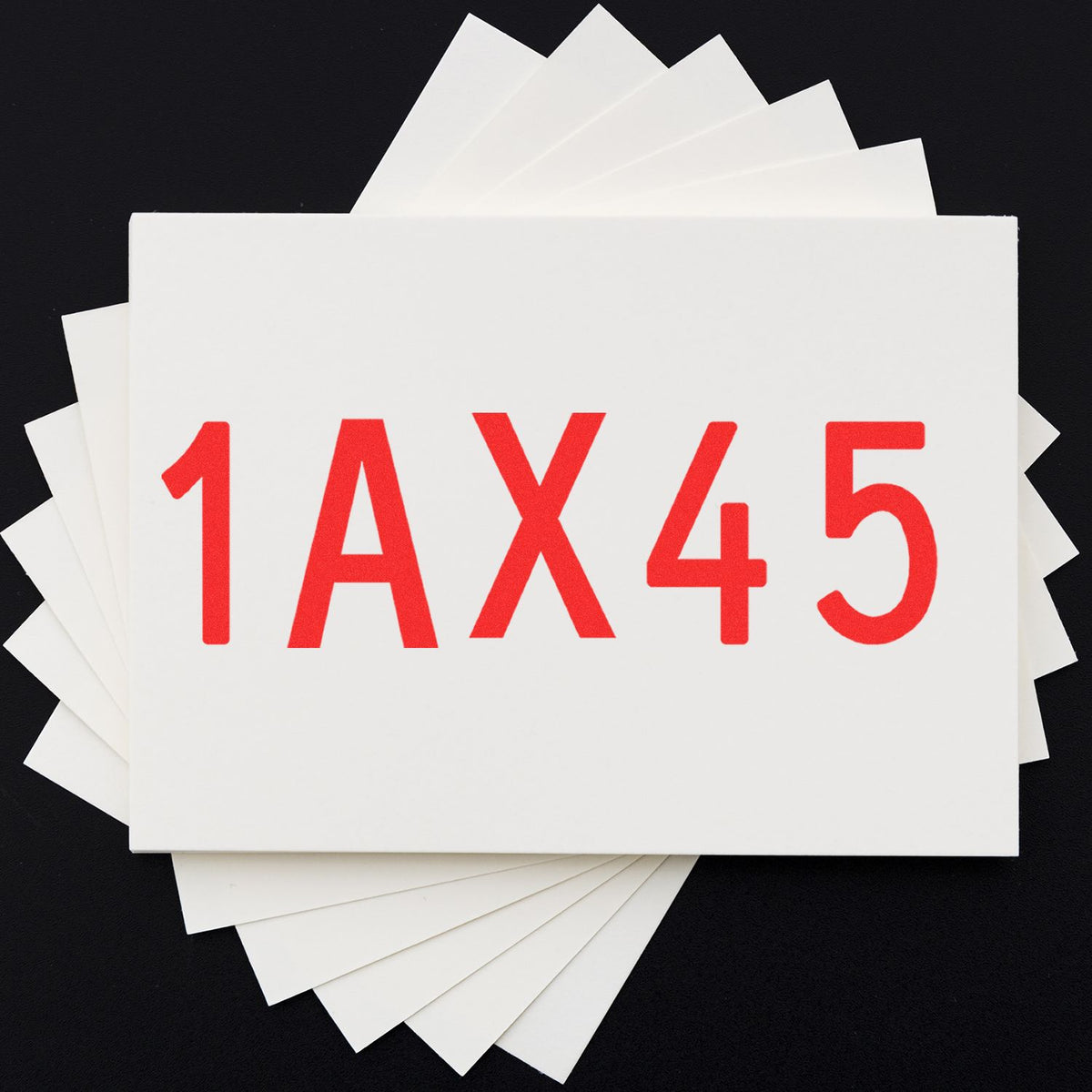 White fan of stamp and seal sample cards with red 1AX45 code on a black background.