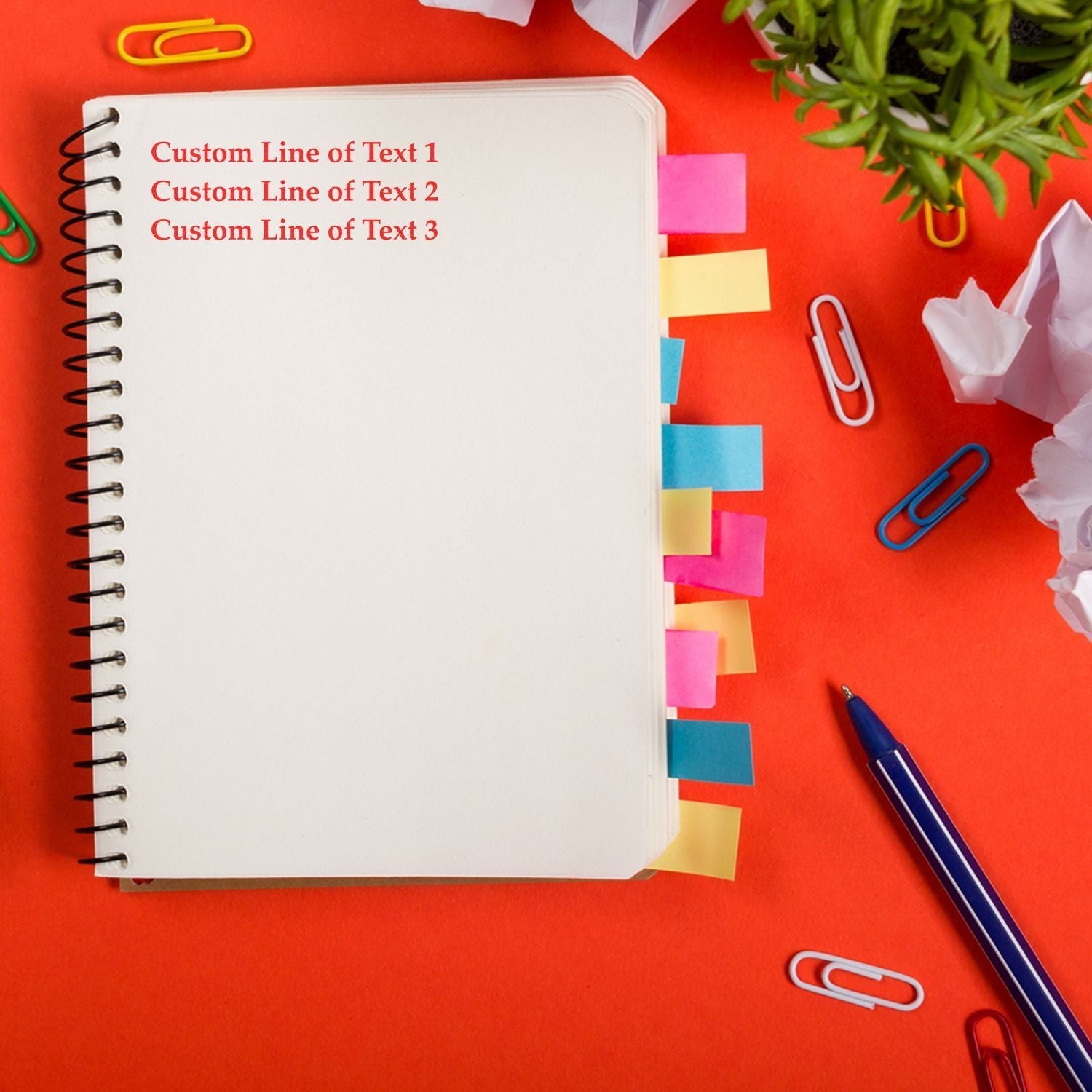 3 Line Custom Rubber Stamp with Wood Handle used on a notebook with colorful tabs, surrounded by paper clips, a pen, and a plant.