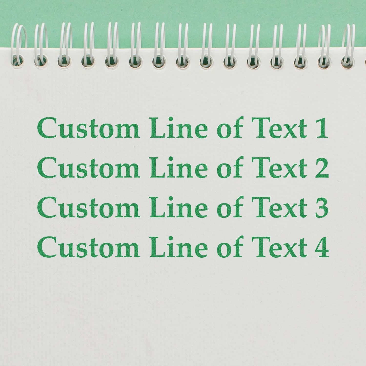 A 4 Line Custom Rubber Stamp with Wood Handle imprints green text on a white spiral notebook, showing four customizable lines.