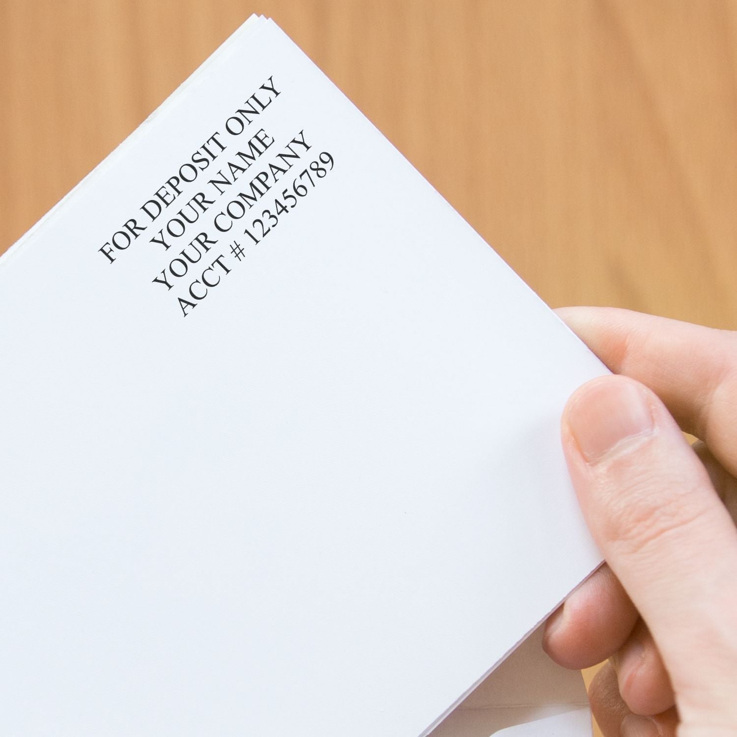 A hand holding a check stamped with FOR DEPOSIT ONLY YOUR NAME YOUR COMPANY ACCT #123456789 using a 4 Line Self Inking Check Endorsement Stamp.