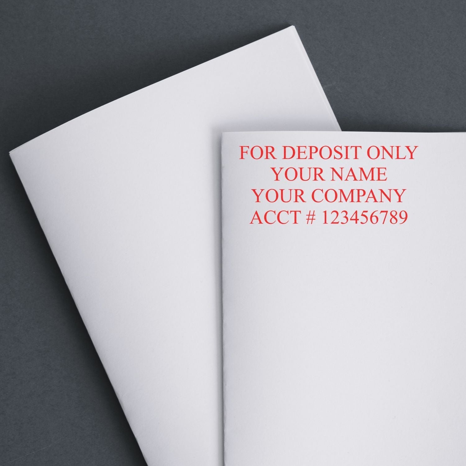 4 Line Self Inking Check Endorsement Stamp in red ink on a white checkbook, displaying FOR DEPOSIT ONLY YOUR NAME YOUR COMPANY ACCT # 123456789 .