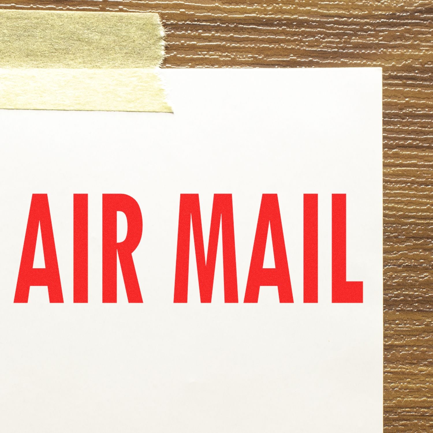 Large Pre-Inked Air Mail Stamp in red ink on white paper, taped to a wooden surface with masking tape.