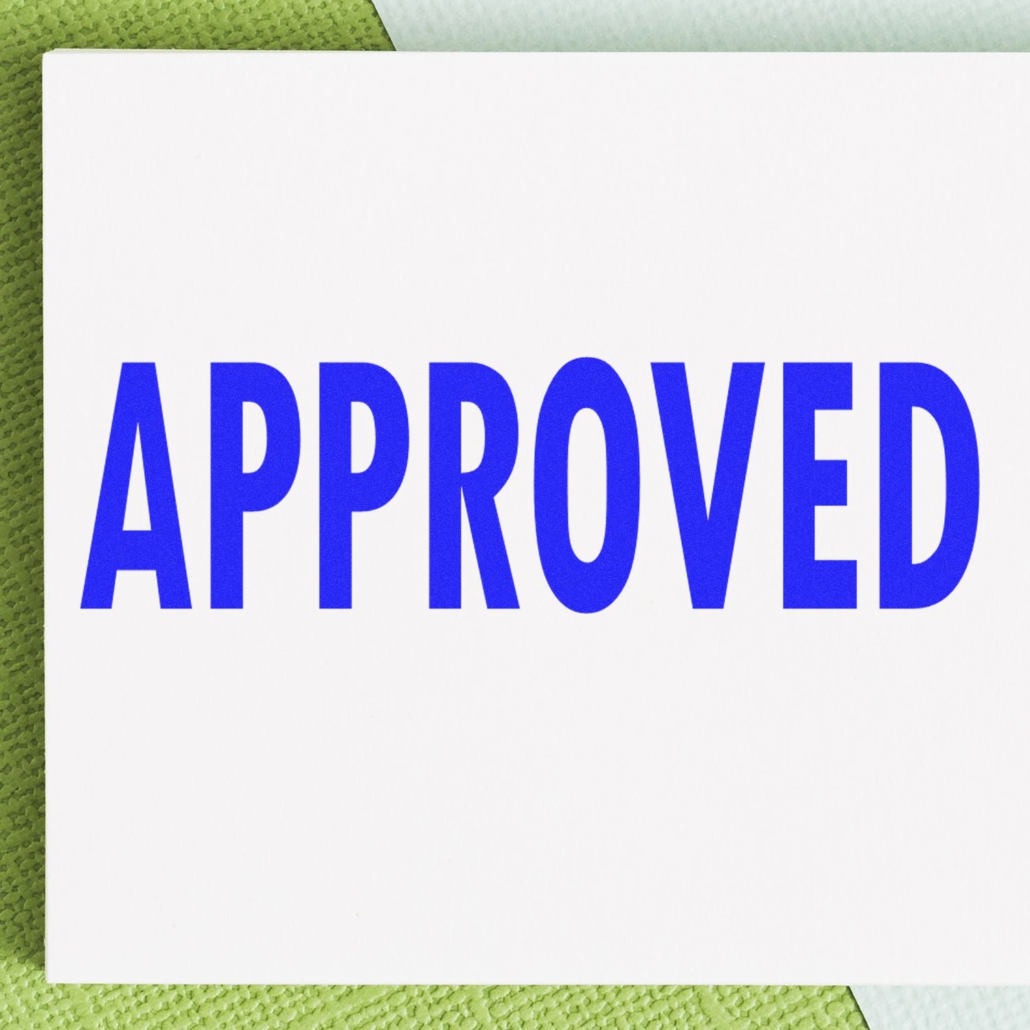 Large Pre-Inked Approved Stamp in blue ink on white paper, placed on a green textured surface.