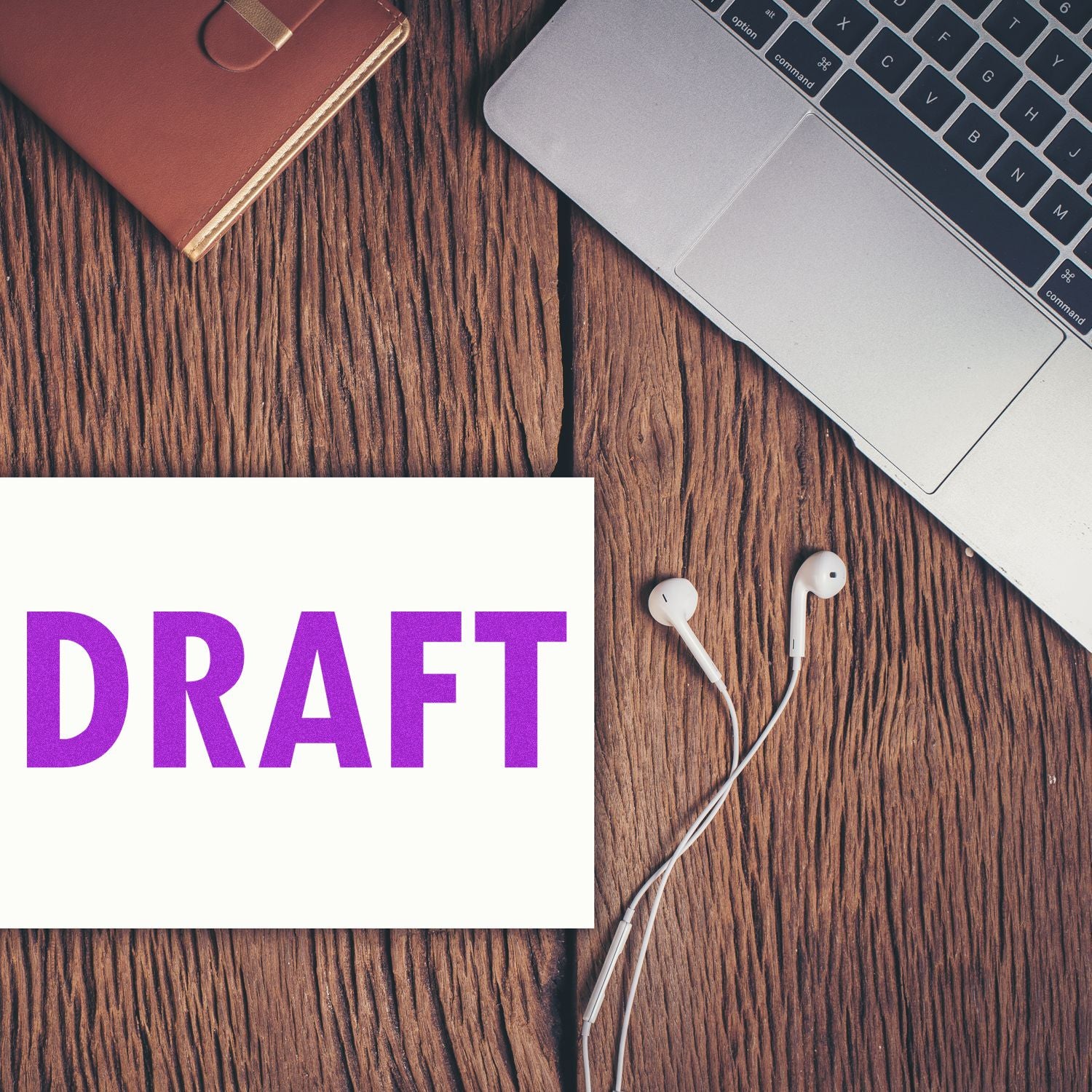 Large Pre-Inked Draft Stamp in purple ink on paper, placed on a wooden desk beside a laptop, earphones, and a brown notebook.