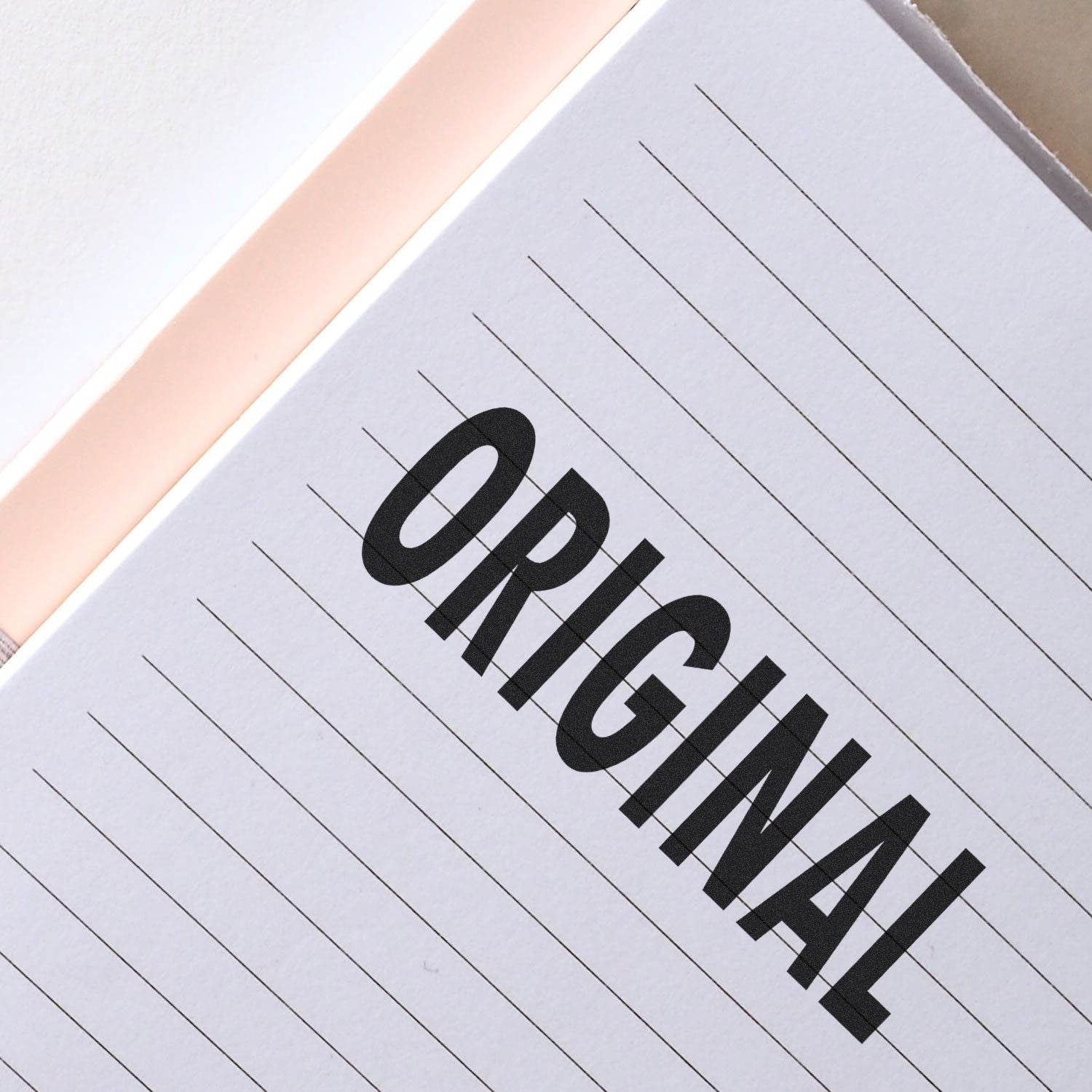 Close-up of a notebook with the word ORIGINAL stamped in bold black letters using the Large Pre-Inked Original Stamp.