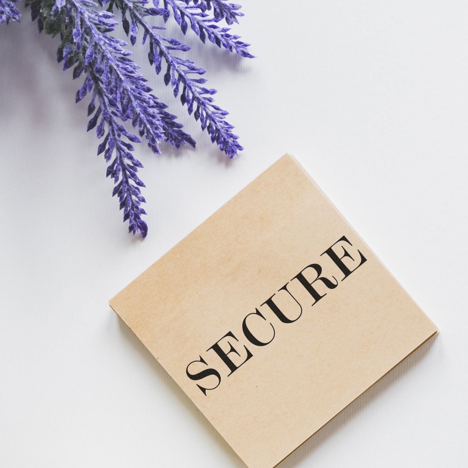 Large Pre-Inked Secure Stamp on a beige square pad with SECURE text, placed next to purple lavender flowers on a white background.