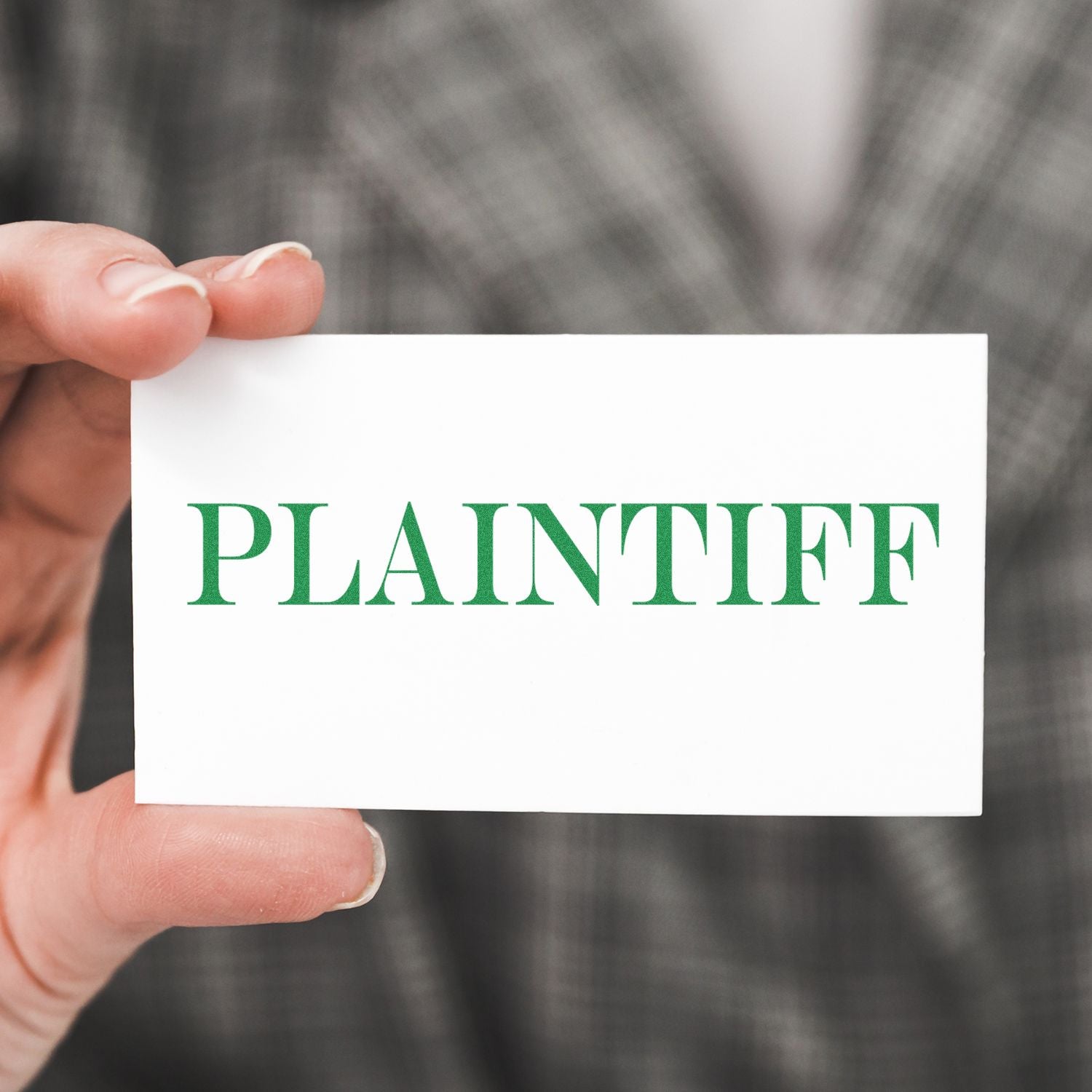 A hand holding a white card with the word PLAINTIFF in green, stamped using the Large Pre-Inked Plaintiff Stamp.