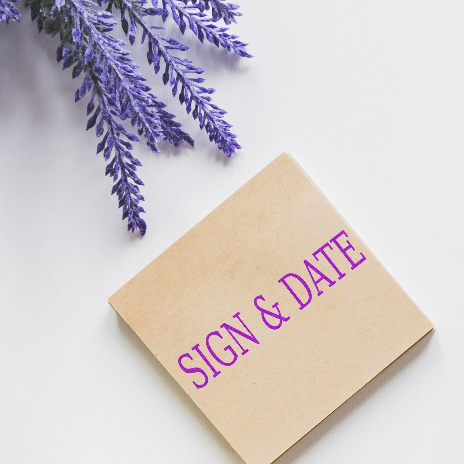 Large Pre-Inked Sign & Date Stamp on a white surface with purple flowers in the background.