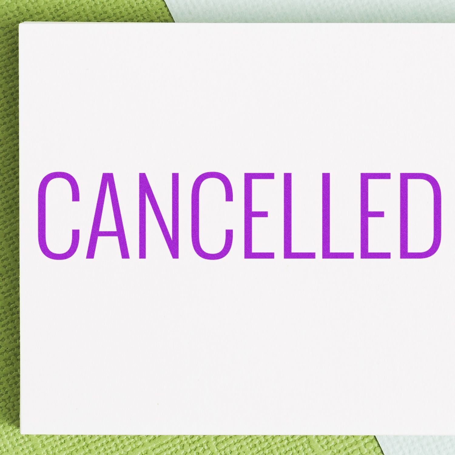 Large Pre-Inked Narrow Font Cancelled Stamp with purple text on white paper, placed on a green and white background.