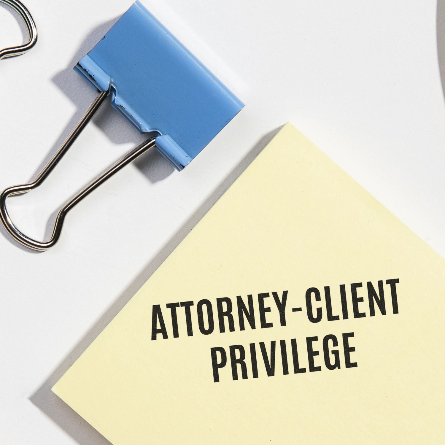 Large Pre-Inked Attorney-Client Privilege Stamp on a yellow paper next to a blue binder clip on a white surface.