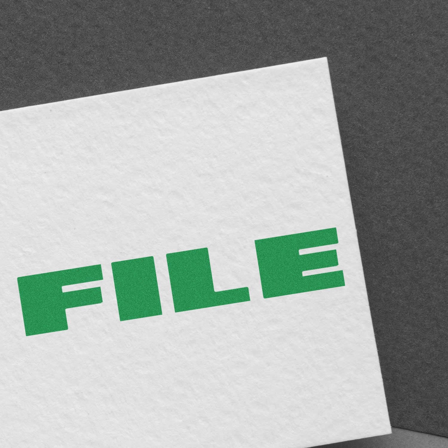 Large Pre-Inked Bold Font File Stamp in green ink on white paper, angled on a dark gray background.