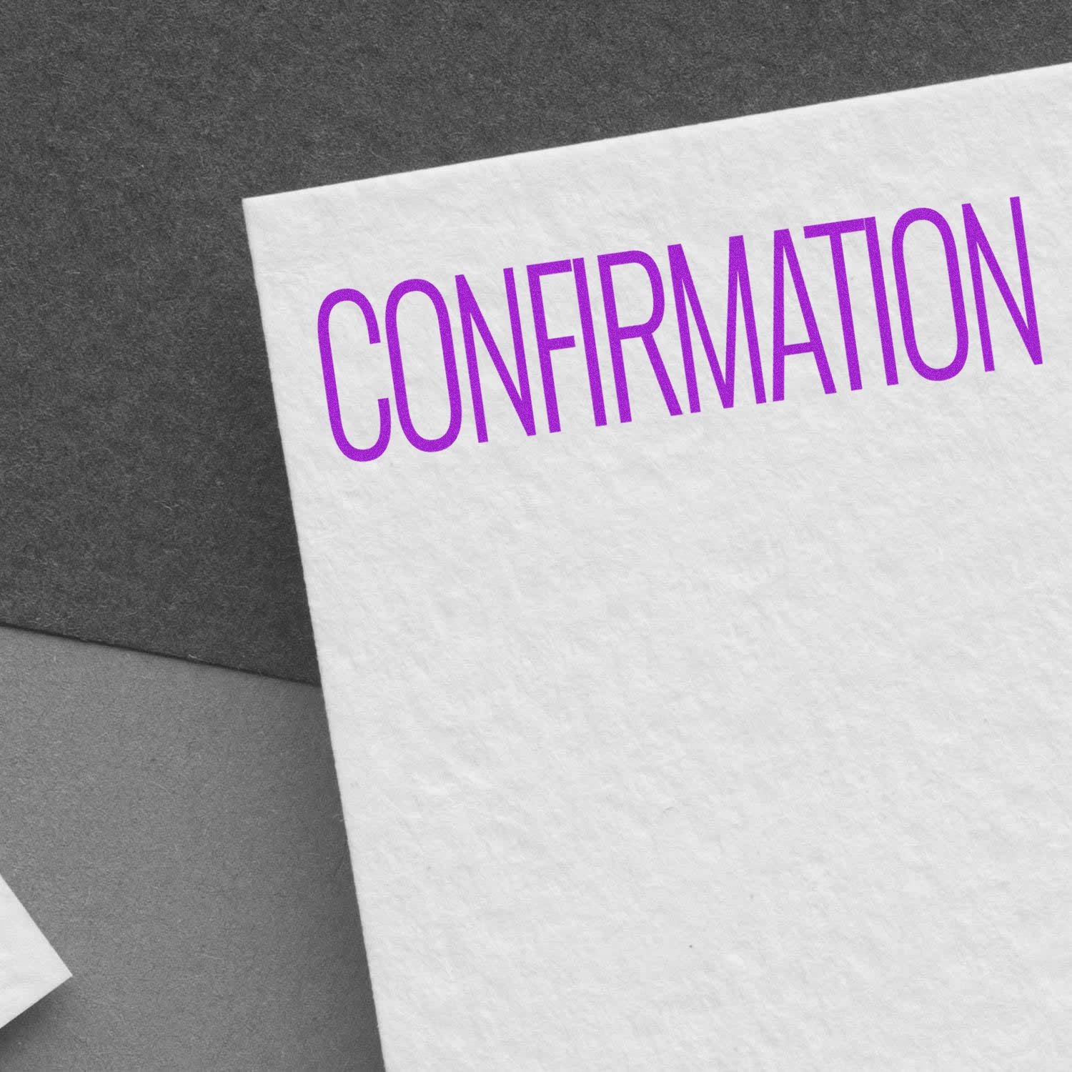 Large Pre-Inked Confirmation Stamp imprinting the word CONFIRMATION in purple on a textured white paper, placed on a gray surface.