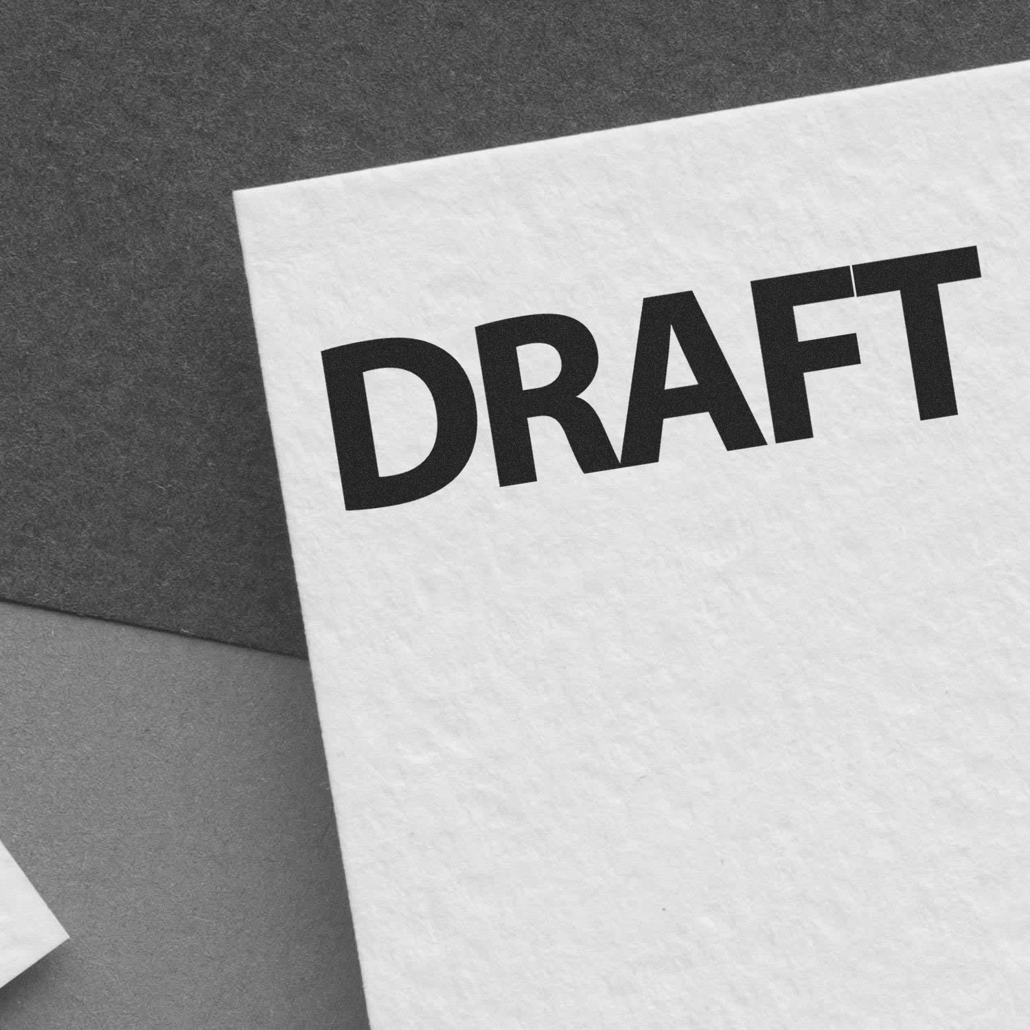 Large Pre-Inked Bold Draft Stamp marking DRAFT in bold black letters on a white paper, placed on a gray background.