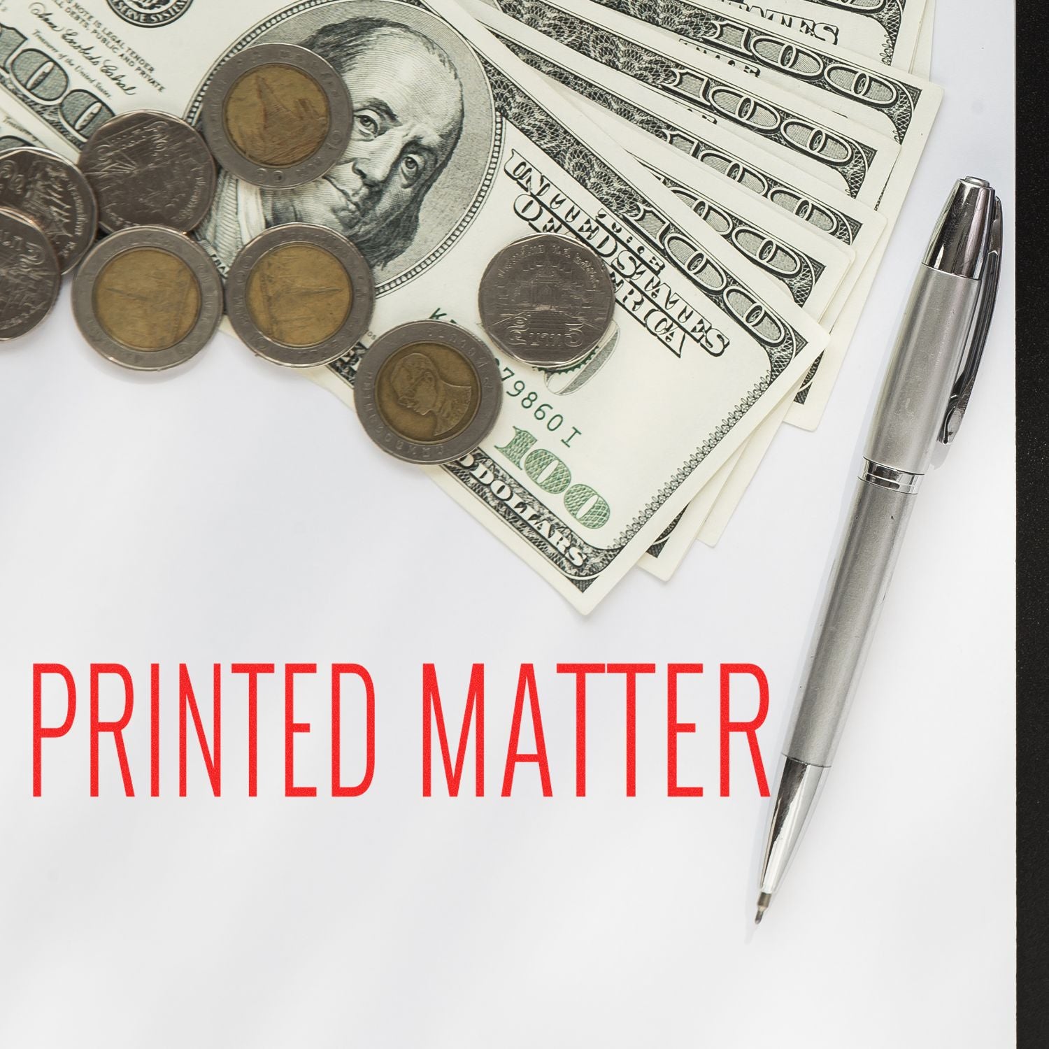 Large Pre-Inked Printed Matter Stamp next to a pen, coins, and dollar bills on a white surface with PRINTED MATTER text in red.