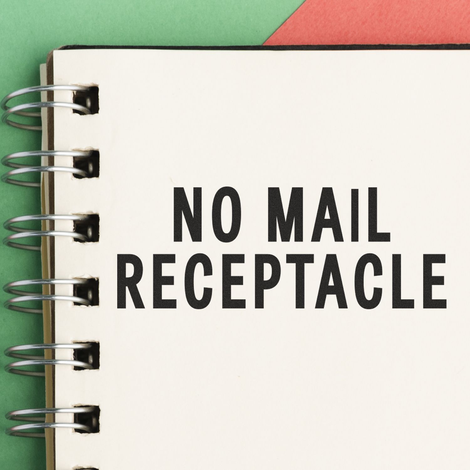 Large Pre-Inked No Mail Receptacle Stamp on a spiral notebook with a green and red background.