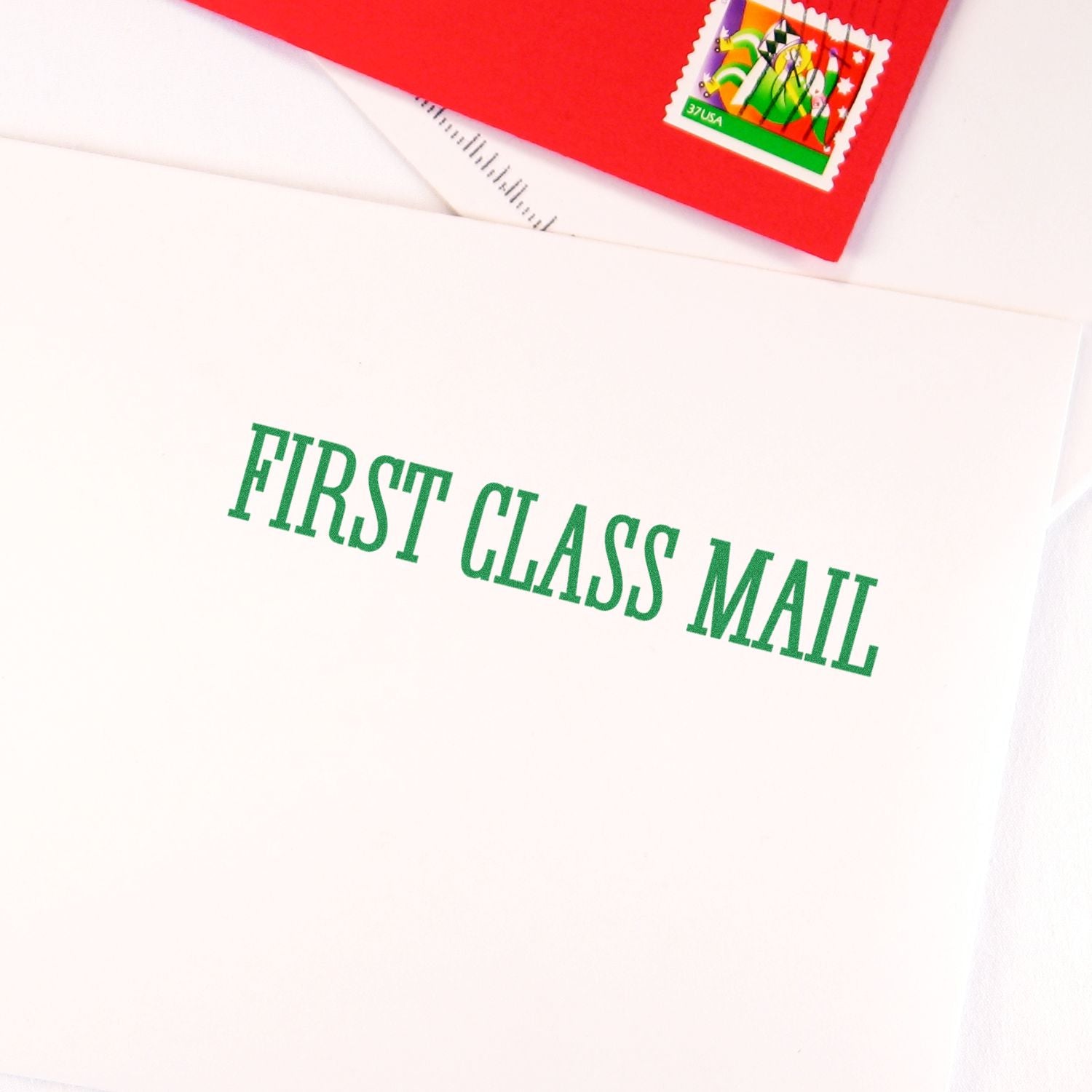 Large Pre-Inked Times First Class Mail Stamp used on a white envelope with green text, next to a red envelope with a colorful stamp.