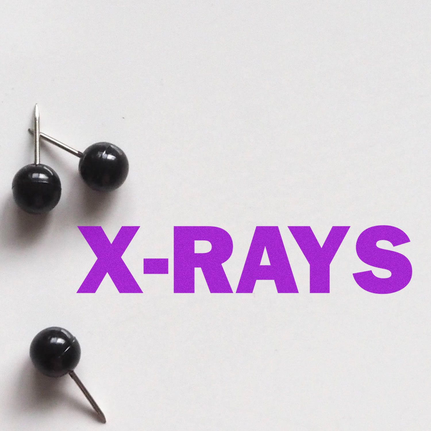 Large Pre-Inked X-Rays Stamp with bold purple text X-RAYS on a white background, accompanied by three black push pins.