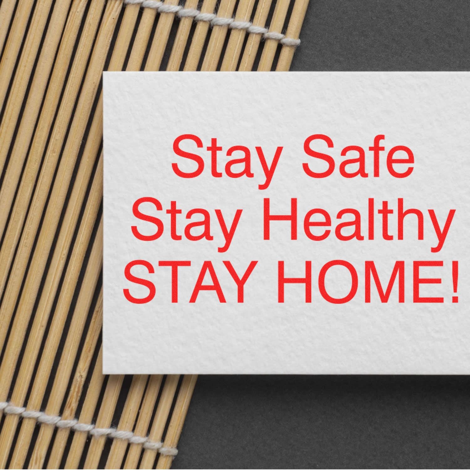 Large Pre-Inked Stay Safe Stay Healthy Stamp in red ink on a white card, placed on a bamboo mat background.