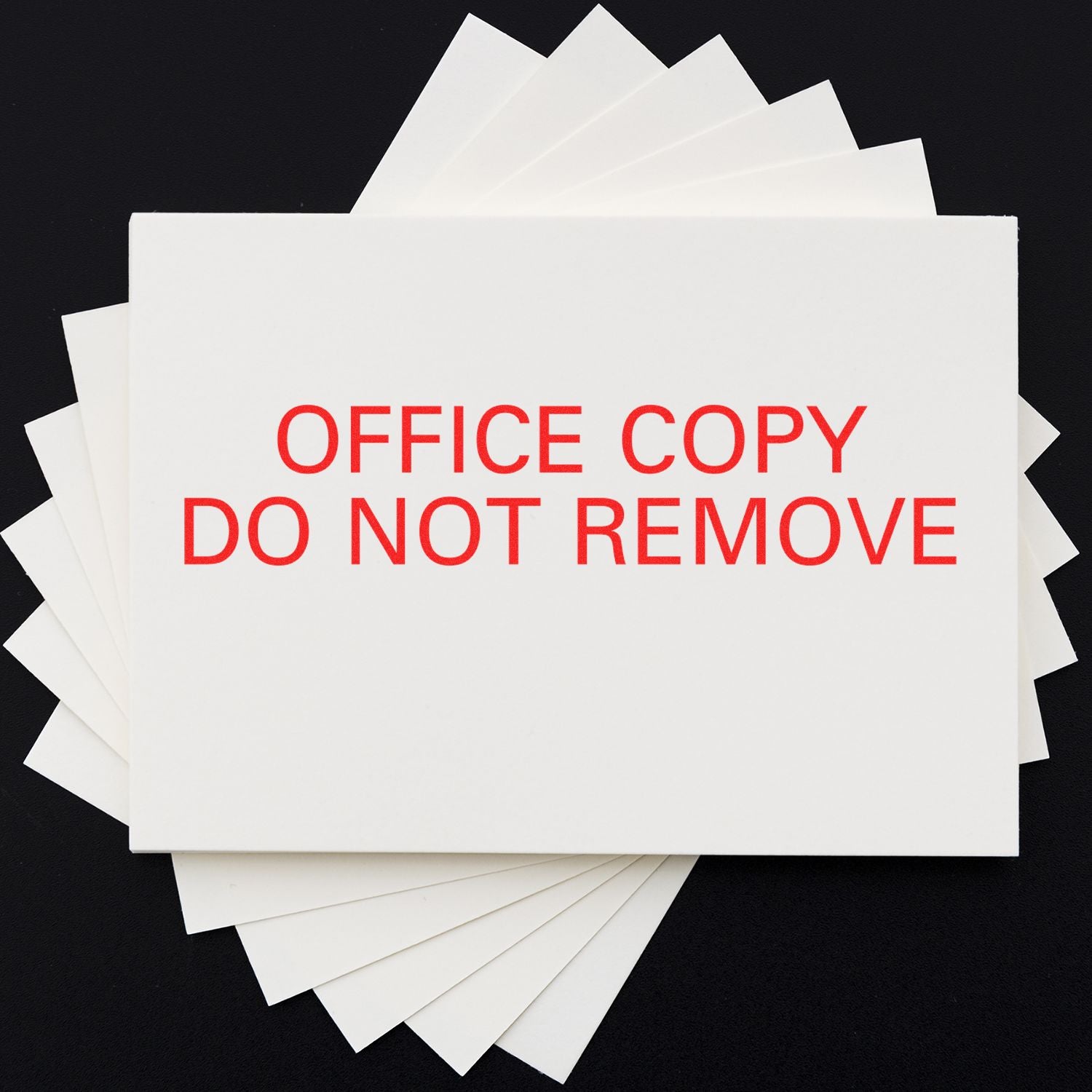 Large Self Inking Office Copy Do Not Remove Stamp in red ink on a white card, with multiple cards stacked underneath on a black background.