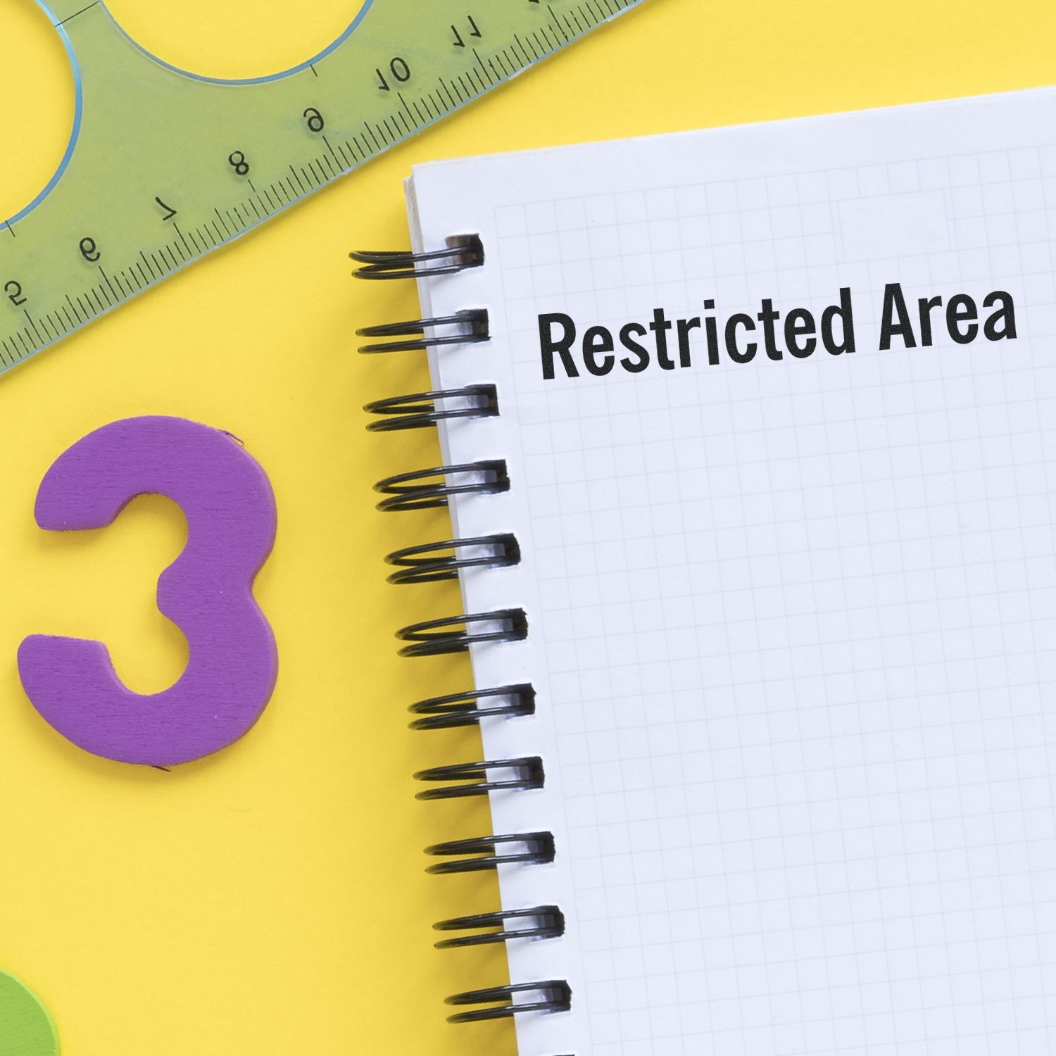 Large Self Inking Restricted Area Stamp marking a notebook page with Restricted Area text, alongside a ruler and a purple number 3 on a yellow background.