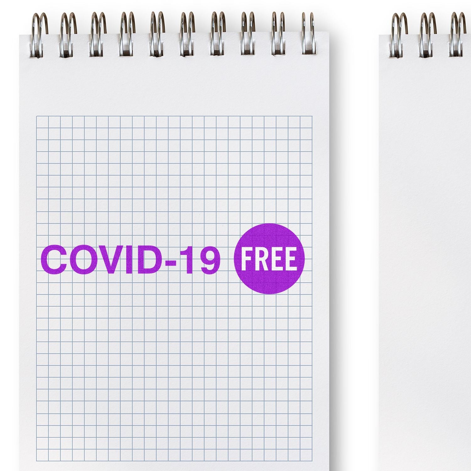 A notebook with a grid pattern page stamped COVID-19 FREE in purple ink using the Large Self Inking Covid-19 Stamp.