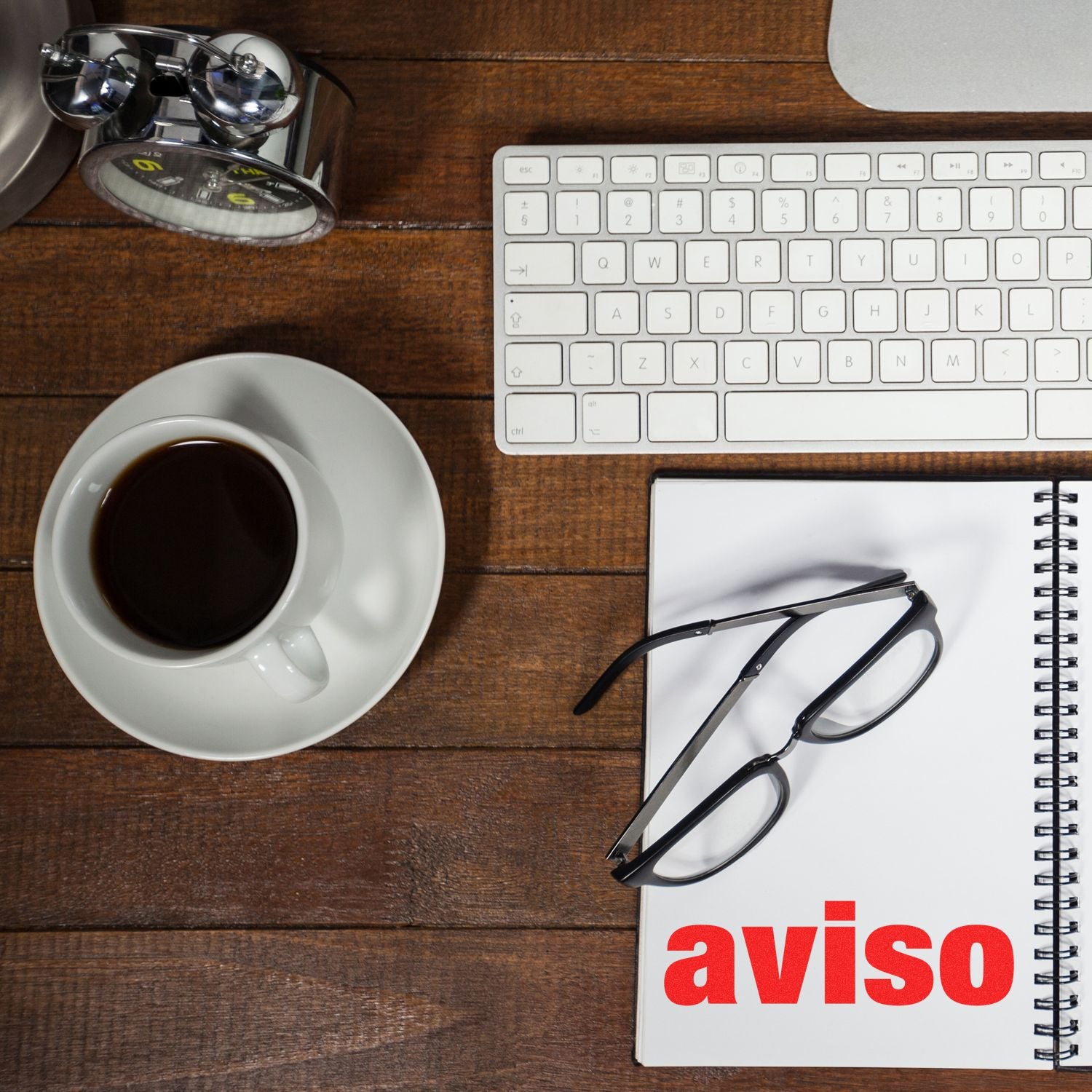 A desk with a keyboard, coffee cup, glasses, and a notebook with aviso text. Large Self Inking Aviso Stamp not shown but implied.