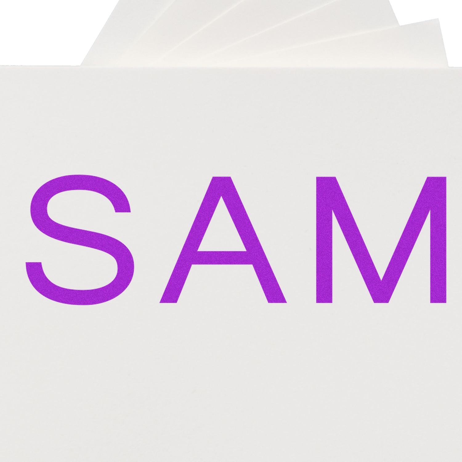 Large Pre-Inked SAM Stamp with purple SAM text on a white background, partially visible stamp pads in the background.