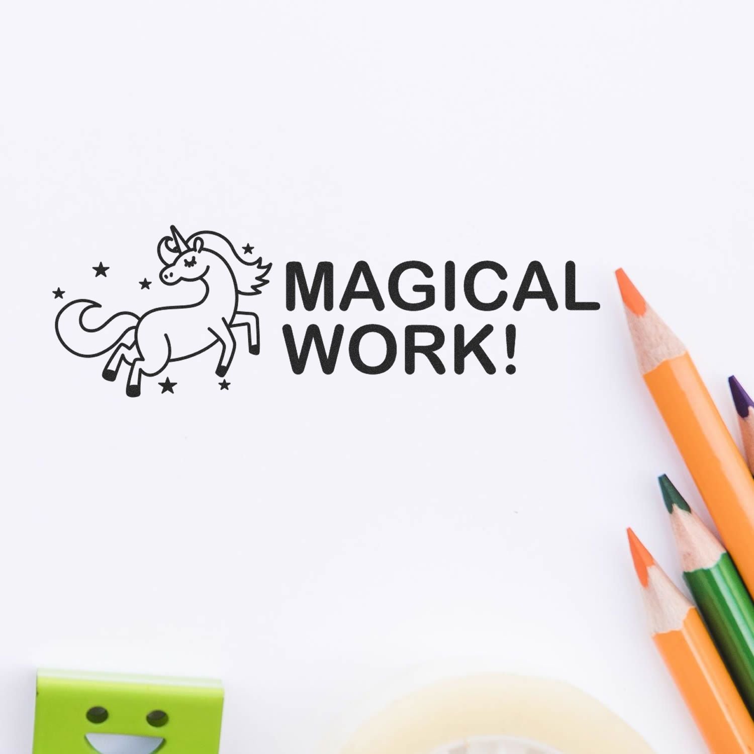 Large Pre-Inked Magical Work Stamp with a unicorn and stars design, stamped on white paper, surrounded by colored pencils and stationery.