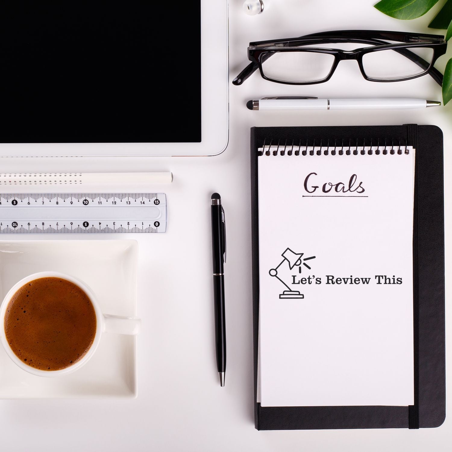 Desk with coffee, tablet, glasses, pen, ruler, and notebook with Goals and Large Pre-Inked Let's Review This with Lamp Stamp on the page.