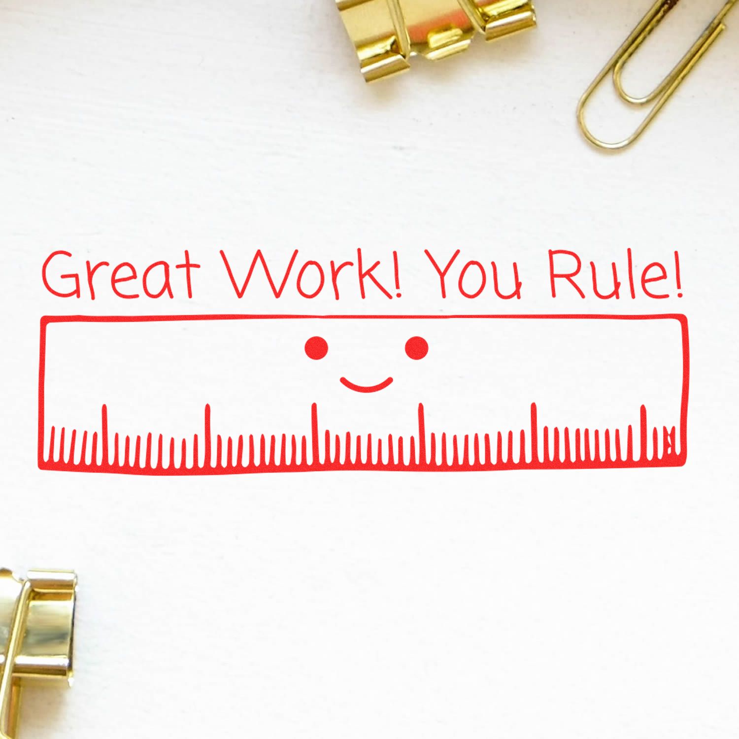 Large Pre-Inked Great Work You Rule Stamp with a smiling ruler and the text Great Work! You Rule! in red ink, surrounded by paper clips.