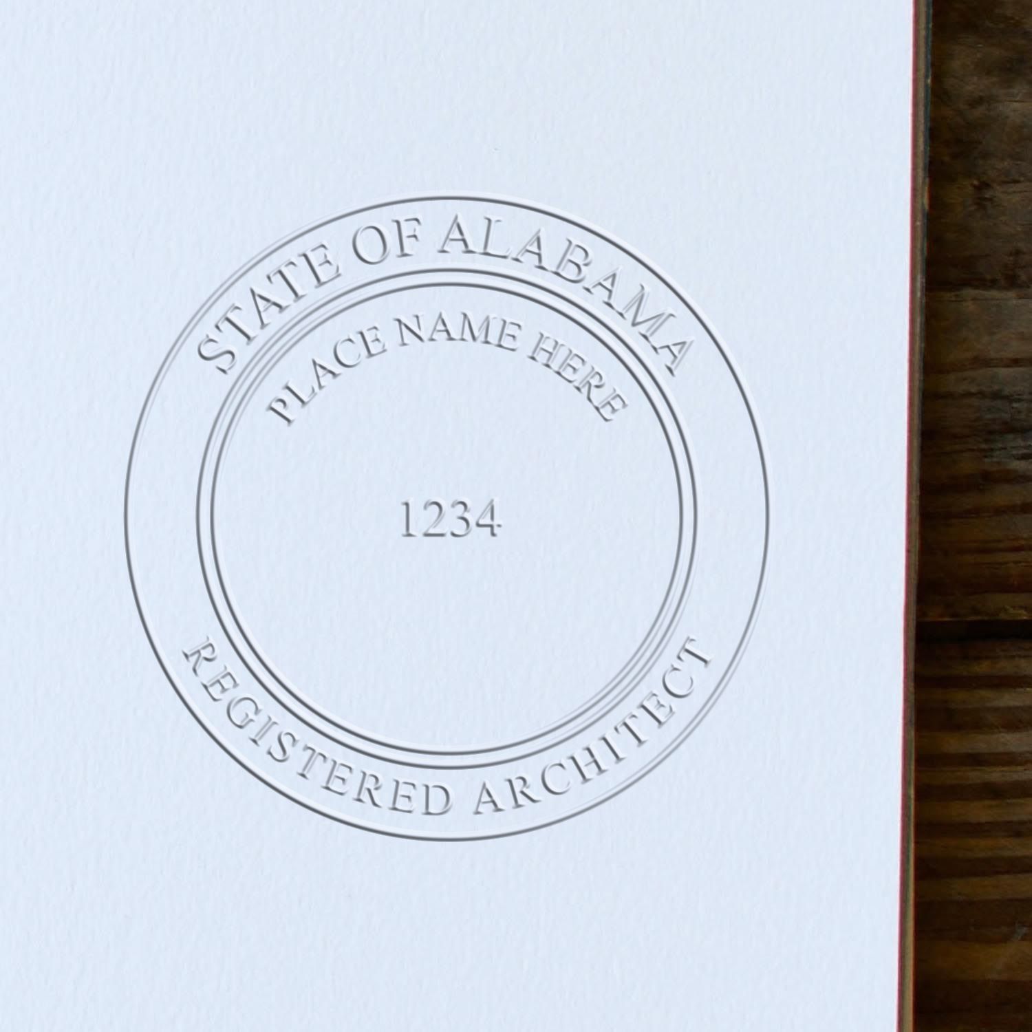 An in use photo of the Hybrid Alabama Architect Seal showing a sample imprint on a cardstock