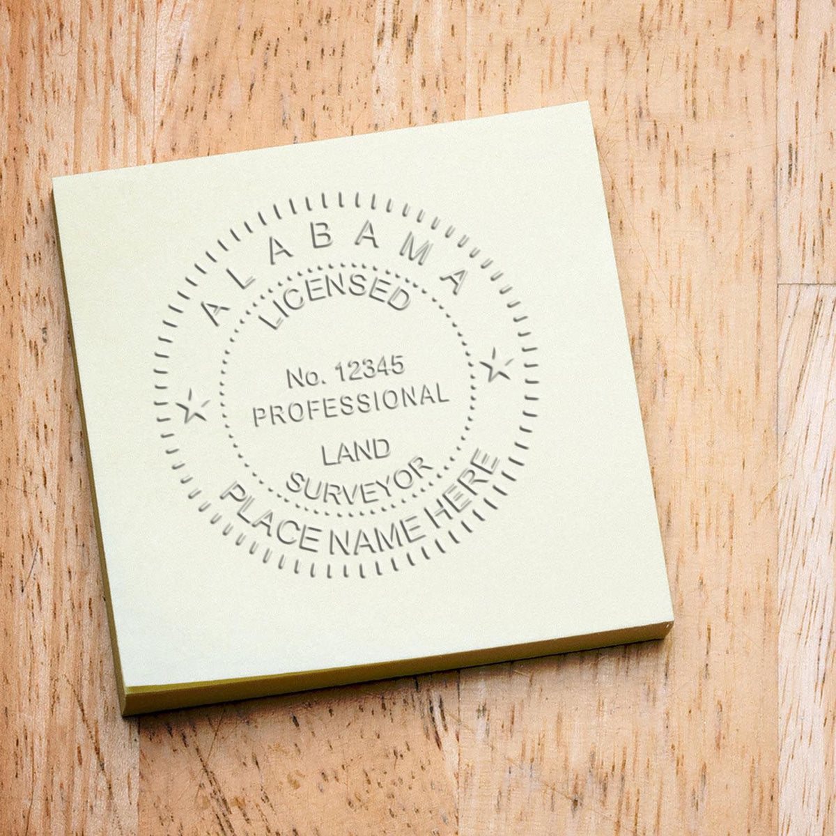 An in use photo of the Gift Alabama Land Surveyor Seal showing a sample imprint on a cardstock