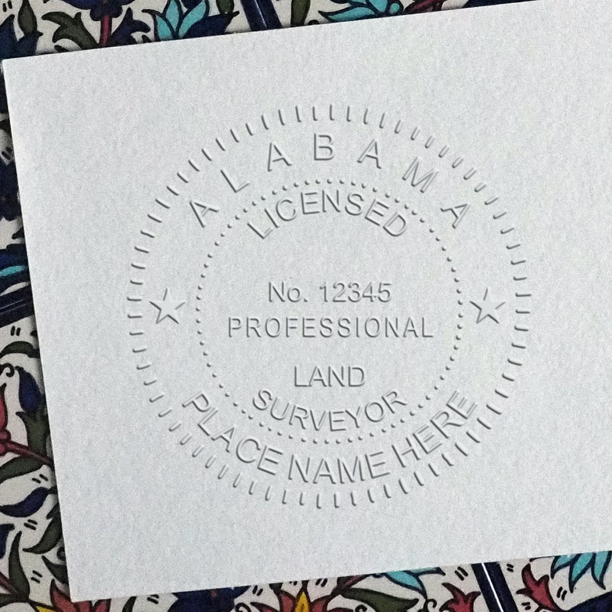 A lifestyle photo showing a stamped image of the Handheld Alabama Land Surveyor Seal on a piece of paper