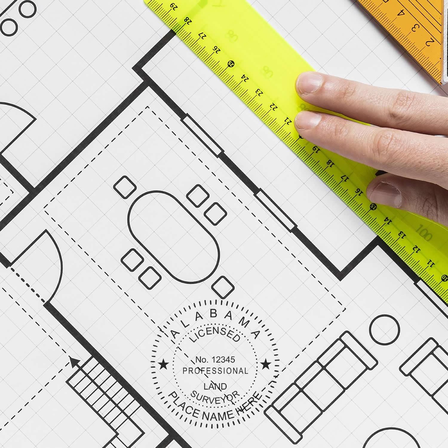 Hand using a ruler on a blueprint with a Premium MaxLight Pre-Inked Alabama Surveyors Stamp marked on the paper.