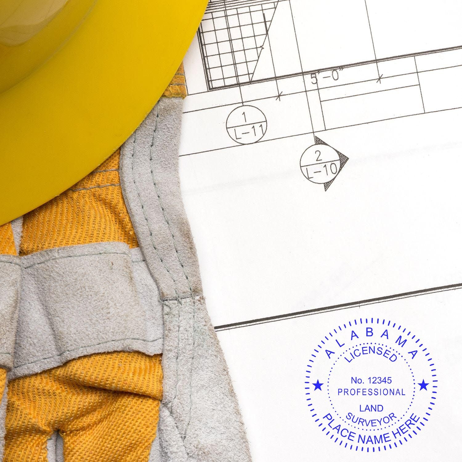 Premium MaxLight Pre-Inked Alabama Surveyors Stamp on a blueprint with a yellow hard hat and gloves nearby.