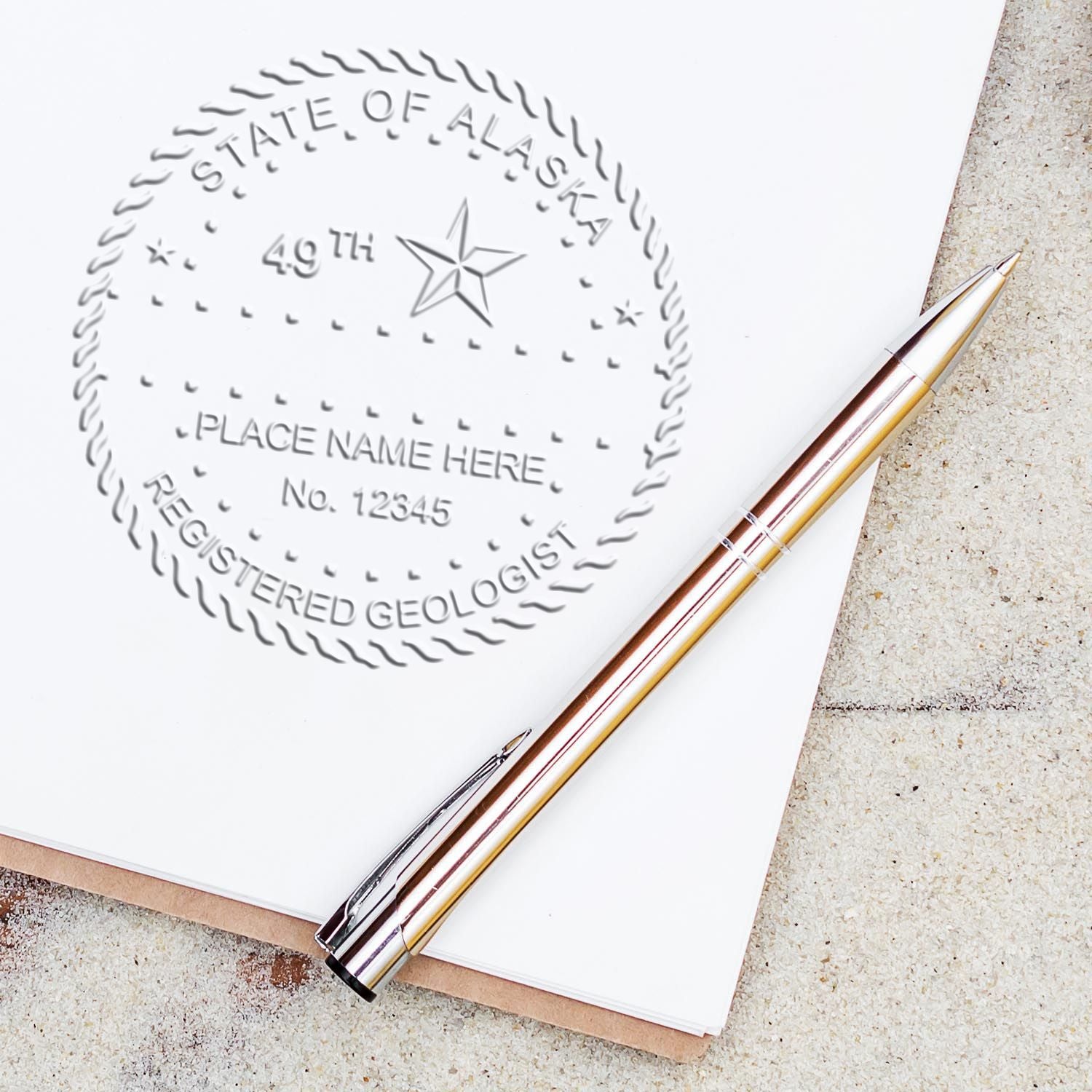 An in use photo of the Alaska Geologist Desk Seal showing a sample imprint on a cardstock