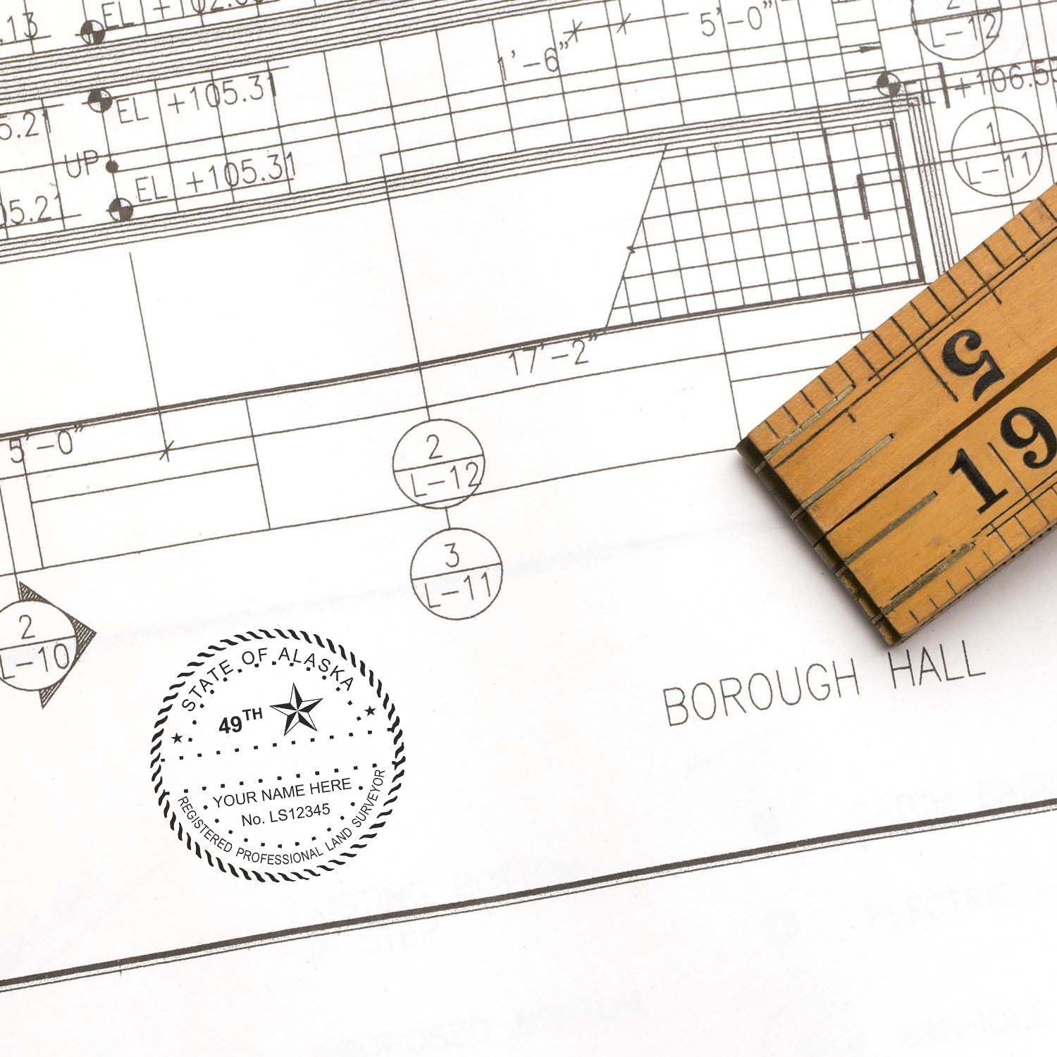 Blueprint with a Digital Alaska Land Surveyor Stamp, Electronic Seal for Alaska Land Surveyor, and a wooden ruler on the side.