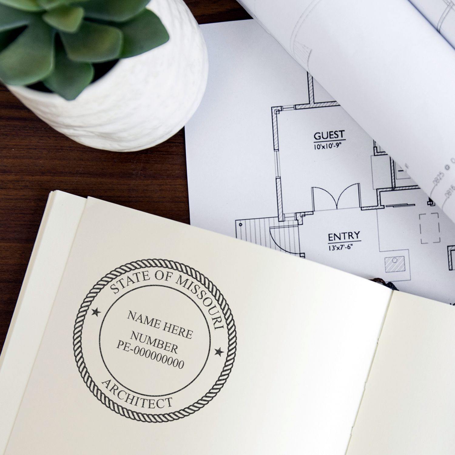 Architect MaxLight Pre Inked Rubber Stamp of Seal in use on an architectural document, with a floor plan and a potted plant in the background.