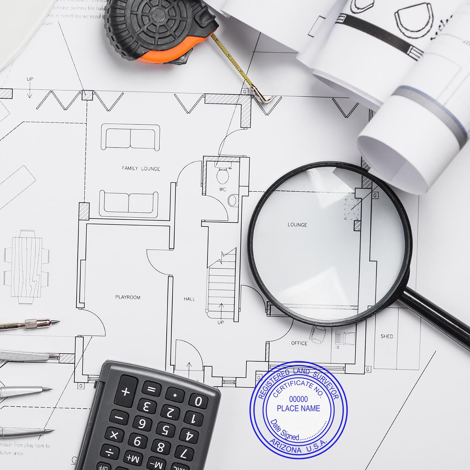 Self Inking Arizona Land Surveyor Stamp on a blueprint with a magnifying glass, calculator, and drafting tools.