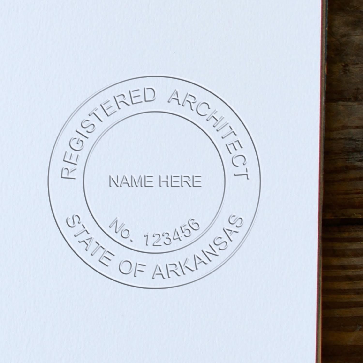 A lifestyle photo showing a stamped image of the Handheld Arkansas Architect Seal Embosser on a piece of paper