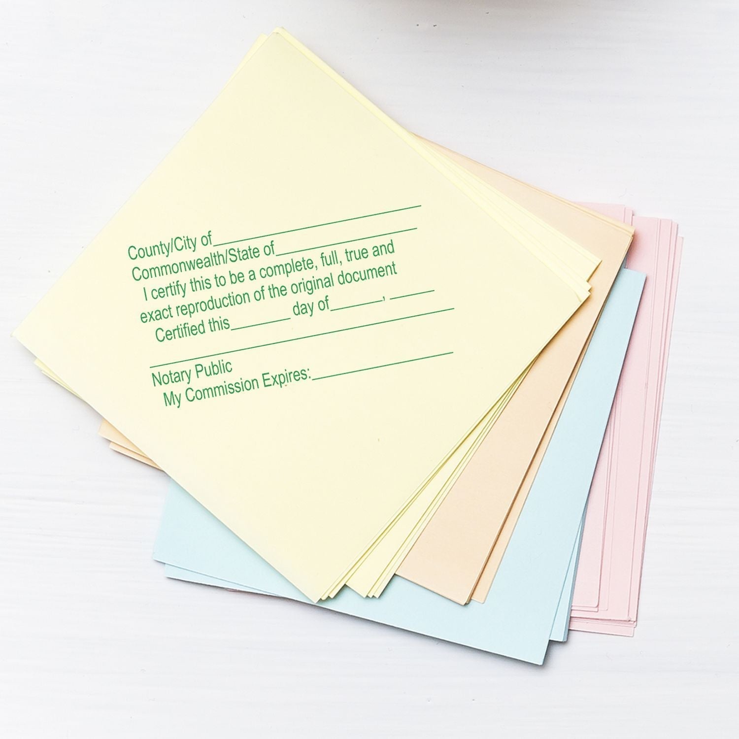 A stack of pastel-colored papers stamped with the Self Inking Notary Certified Copy Stamp, showing certification text and blank fields for details.